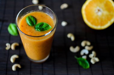 Koyu arkaplanda elma, havuç ve fındıklı taze çiğ portakal suyu.