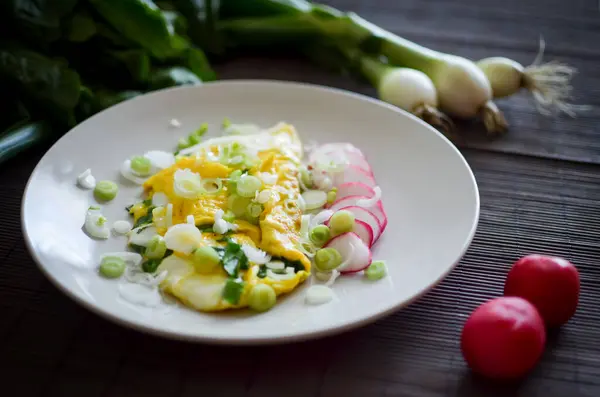 Koyu arkaplanda peynirli, ıspanaklı, soğanlı ve turplu omlet.