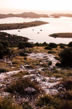 Hırvatistan, Avrupa 'daki ünlü Kornati ulusal parkının üzerinde güzel bir gün batımı, Zut adasının tepesinden manzara, denizde yelkenliler, sakin bir akşam.