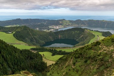 Sao Miguel adasının arka planında Sete Cidades gölünün daha büyük olduğu Santiago Gölü 'nün panoramik manzarası. Azores takımadaları, Portekiz.