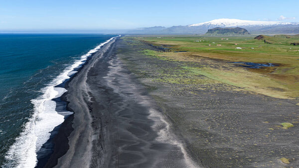 Long black beach seen from the Dyrholaey promontory with Eyafjiallajokull volcano in the background
