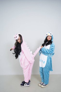 İki Asyalı kadın kostüm giymiş ve beyaz arka planda bir tavşan tutuyorlar.