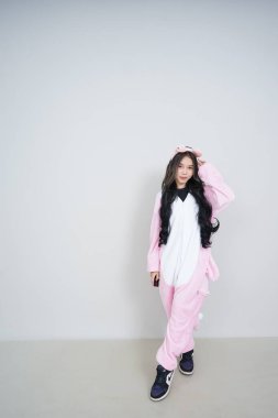 Uzun siyah saçlı, beyaz pijamalı, siyah pijamalı ve oyuncak ayılı Asyalı genç bir kadın.