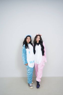 Pembe arka planda mavi pijama giyen genç ve güzel Asyalı kadınlar..