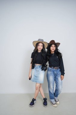 Şapka ve kot pantolon giyen iki güzel Asyalı genç kız.