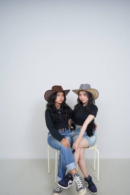 İki güzel Asyalı genç kadın, bacakları odada yerde oturuyor.