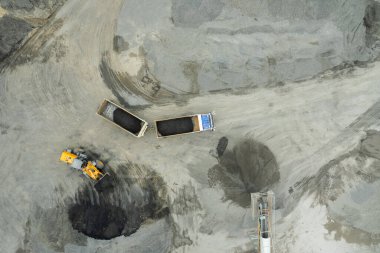 Kum yükleyicileri çöp kamyonlarına taş topluyor.