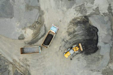 Kum yükleyicileri çöp kamyonlarına taş topluyor.