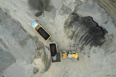 Kum yükleyicileri çöp kamyonlarına taş topluyor.