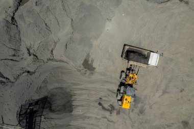 Kum yükleyicileri çöp kamyonlarına taş topluyor.