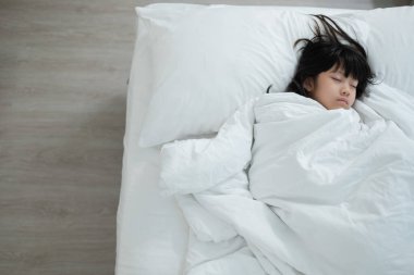 Asyalı çocuk yatakta uyuyor, hasta çocuk.