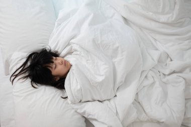 Asyalı çocuk yatakta uyuyor, hasta çocuk.