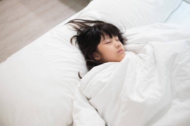 Asyalı çocuk yatakta uyuyor, hasta çocuk.