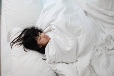 Asyalı çocuk yatakta uyuyor, hasta çocuk.