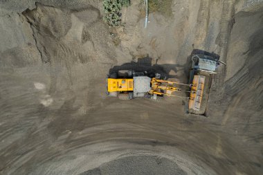 Kum yükleyicileri çöp kamyonlarına taş topluyor.