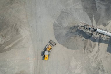 Kum yükleyicileri çöp kamyonlarına taş topluyor.