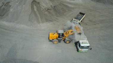 Kum yükleyicileri çöp kamyonlarına taş topluyor.