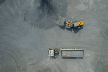 Kum yükleyicileri çöp kamyonlarına taş topluyor.