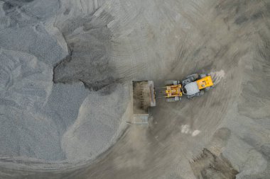 Kum yükleyicileri çöp kamyonlarına taş topluyor.