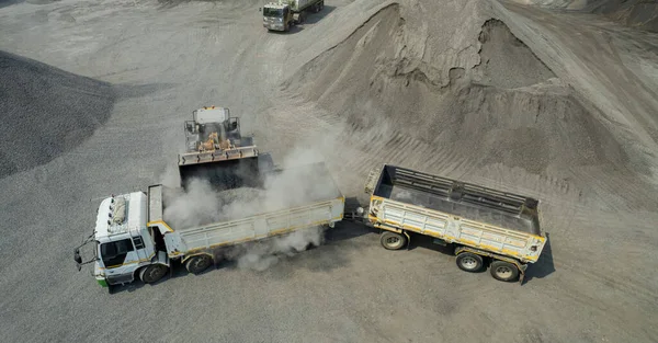 Sand loaders are shoveling rocks into dump trucks