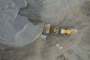 Kum yükleyicileri çöp kamyonlarına taş topluyor.