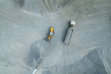 Kum yükleyicileri çöp kamyonlarına taş topluyor.