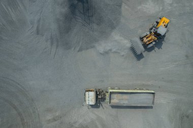 Kum yükleyicileri çöp kamyonlarına taş topluyor.