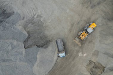 Kum yükleyicileri çöp kamyonlarına taş topluyor.