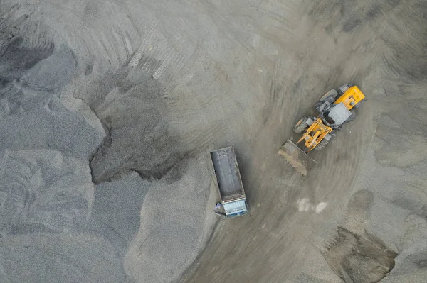 Sand loaders are shoveling rocks into dump trucks