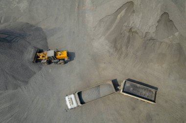 Kum yükleyicileri çöp kamyonlarına taş topluyor.