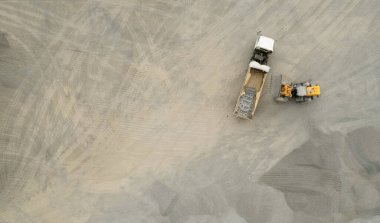 Kum yükleyicileri çöp kamyonlarına taş topluyor.