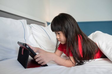 Çocuk yatakta tablet izliyor, çocuk müptelası araba da