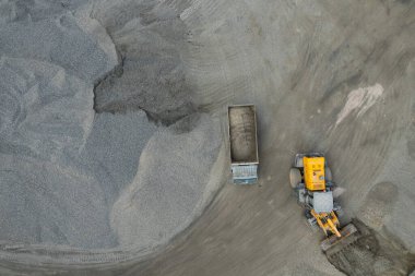 Kum yükleyicileri çöp kamyonlarına taş topluyor.