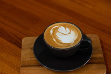 Tahta masada sıcak latte sanat kahvesi, rahatla Tim.