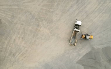 Kum yükleyicileri çöp kamyonlarına taş topluyor.