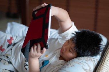 Asyalı Çinli çocuk akıllı telefon oynuyor, çocuk telefon kullanıyor ve oyun oynuyor, bağımlı oyun ve araba kullanıyor.