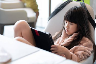 Çocuk yemek masasında tablet izliyor, çocuklar da araba bağımlısı.