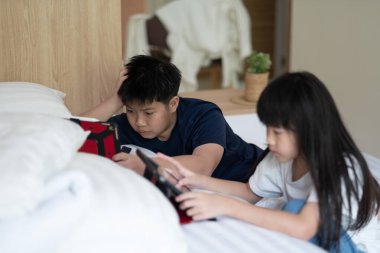 İki Çinli çocuk bağımlı tablet, Asyalı çocuk birlikte telefon izliyor, akıllı telefon kullanıyor.