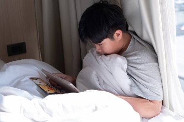 Asyalı Çinli çocuk akıllı telefon oynuyor, çocuk telefon kullanıyor ve oyun oynuyor, bağımlı oyun ve araba kullanıyor.