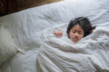 Asyalı çocuk yatakta uyuyor, hasta çocuk.