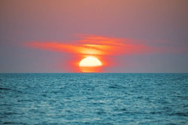 Sunset. Big sun on horizon. Red clouds on the sky. Beautiful seascape. Ocean beach or coast. Florida Gulf of Mexico. Good for travel agency. Spring or summer vacation. Orange sunlight. Tropical Nature