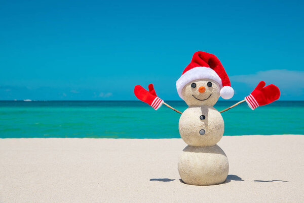 Snowman. Snowman with red Santa Claus hat and mittens. Merry Christmas and Happy New Year. Sandy Snowman on the beach. Smiling snowman. Miami Beach Florida. Celebration Winter Holidays. Xmas postcards