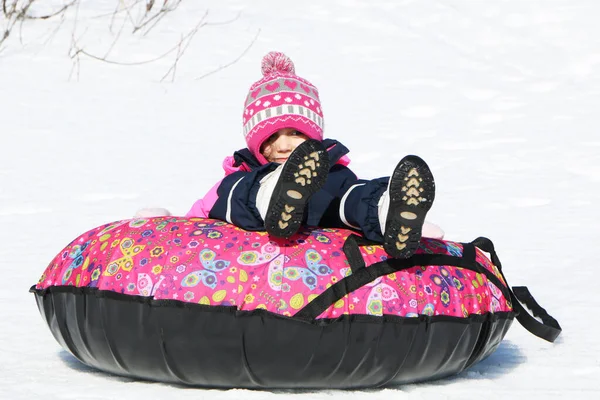 这个孩子在冬天滑行 一个穿着漂亮冬衣的女孩骑在山上 — 图库照片