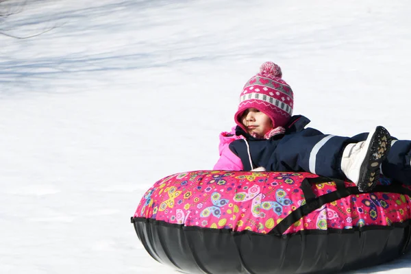 这个孩子在冬天滑行 一个穿着漂亮冬衣的女孩骑在山上 — 图库照片