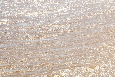 Güneşli deniz kıyısında dalgalar. Güneşin suyun üzerindeki sihirli yansımaları, çok sayıda ışık gibi. Deniz kıyısında güzel bir tatil.