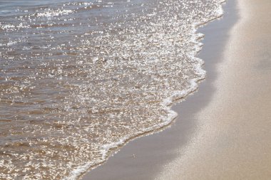 Güneşli deniz kıyısında dalgalar. Güneşin suyun üzerindeki sihirli yansımaları, çok sayıda ışık gibi. Deniz kıyısında güzel bir tatil.