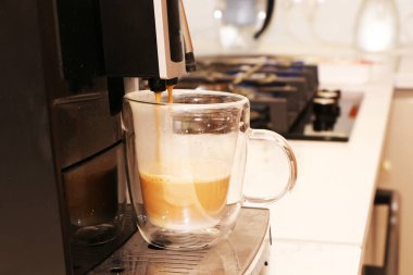 Bir adam otomatik kahve makinesinde aromatik lezzetli kahve hazırlar. Sütlü kahve bir kahve makinesinde hazırlanır..