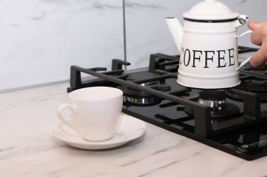 Erkek eller mutfakta kahve dolduruyor. Adam mutfakta bir pastanın arka fonuna kahve döküyor..