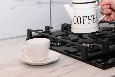 Erkek eller mutfakta kahve dolduruyor. Adam mutfakta bir pastanın arka fonuna kahve döküyor..