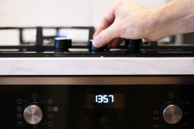 Bir adamın eli mutfak sobasının gazını yakıyor. Bir aşçı yemek pişirmek için gaz sobasını yakar..